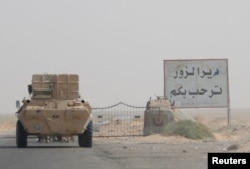 FILE - A road sign welcomes people to the town of Deir el-Zour in Syria, Sept. 20, 2017.