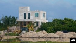 A bulldozer clears a field next to mangroves lining a shoreline near Dzilam de Bravo, in Mexico's Yucatan Peninsula, Oct. 7, 2021. Cutting mangroves has been a crime since 2005. The Yucatan state government said it is aware of complaints of illegal loggin