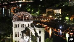 Paper lanterns float down along the Motoyasu River behind the illuminated Atomic Bomb Dome near Hiroshima Peace Memorial Park in Hiroshima, western Japan, Saturday, Aug. 6, 2011