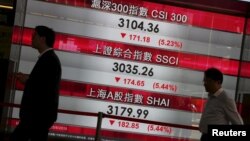 Passers-by walk past a panel displaying falling China stock indexes, at the financial Central district in Hong Kong, China August 25, 2015.