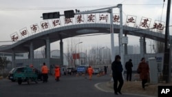  資料照：中國新疆和田居民走過“和田市紡織服裝實訓就業基地”的工廠大門。（2019年10月1日） 