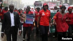 People walk in the rain during a protest for the release of secondary school girls abducted in the remote village of Chibok, along a road in Lagos, May 14, 2014.