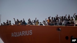 Para migran melambaikan tangan mereka dari atas kapal penyelamat "SOS Mediterranee Aquarius" setelah diselamatkan oleh LSM Proactiva Open Arms, 21 Agustus 2016. (Foto: dok).