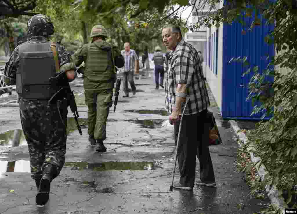 A local man looks on as Ukrainian servicemen pass nearby in the eastern town of Dzerzhinsk, near Donetsk, Aug. 28, 2014.