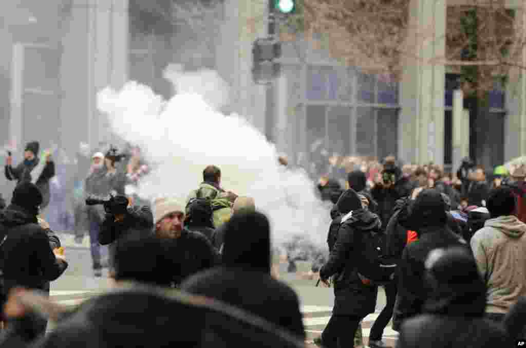 Police deploy smoke and pepper grenades during clashes with protesters in northwest Washington, Friday, Jan. 20, 2017. (AP Photo/Mark Tenally)