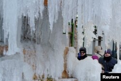 People stop to photograph the frozen Josephine Shaw Lowell Memorial Fountain in New York, U.S., January 3, 2018. REUTERS/Lucas Jackson