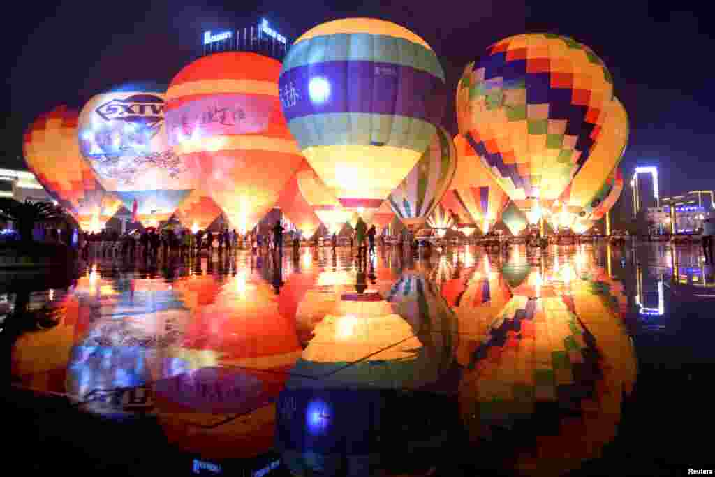 People look at hot air balloons decorating a plaza, during a tourism event in Qianxinan Buyei and Miao Autonomous Prefecture, Guizhou province, China, Oct. 14, 2018.
