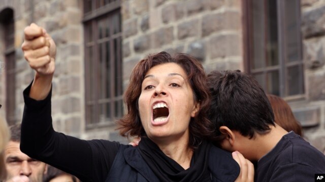 Emel Kitapci, esposa de una de las víctimas de los ataques del sábado reacciona junto a su hijo, Artun Siyah Kitapci, de 11 años, durante una manifestación en el sitio de las explosiones en Ankara, Tuquía, el lunes, 12 de octubre de 2015.


