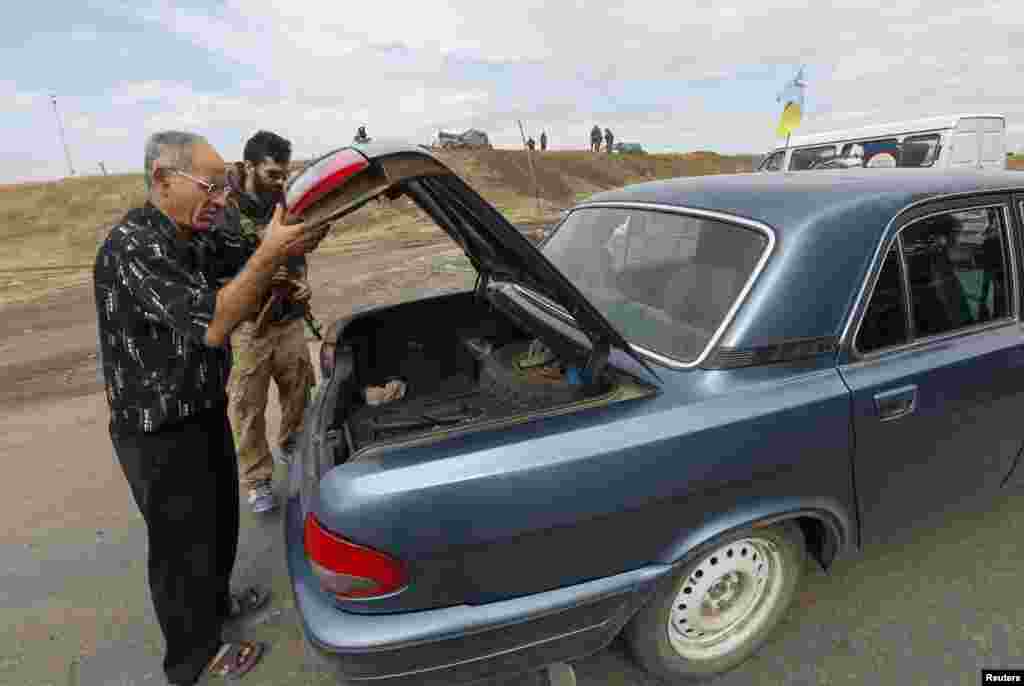 A man opens the boot of a car for an "Azov" soldier at a checkpoint in Mariupol, Sept. 8, 2014.