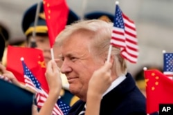 Children wave U.S. and Chinese flags as President Donald Trump arrives at Beijing Airport, Wednesday, Nov. 8, 2017, in Beijing, China.