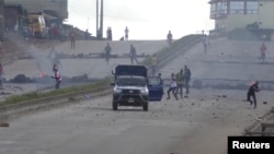 Des manifestants lancent des pierres sur un véhicule de la police anti-émeute sur la route principale du district de Sonfonia à Conakry, en Guinée, le 14 octobre 2019.