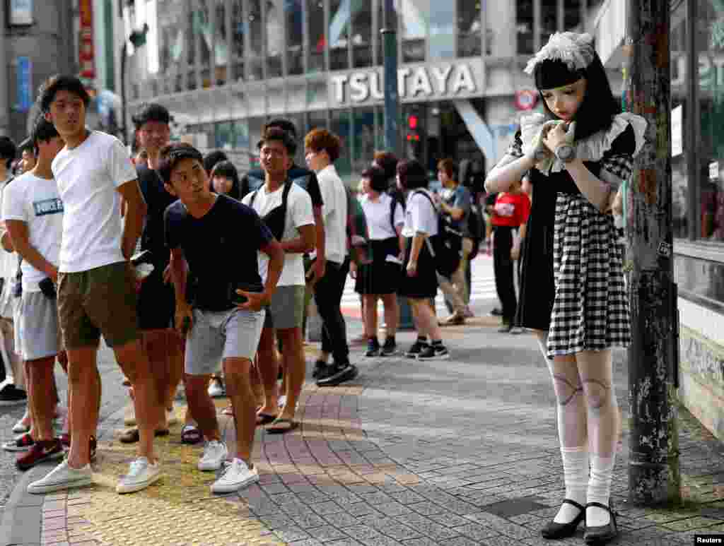 Pedestrians look at &quot;doll&quot; model Lulu Hashimoto standing on the street in Tokyo, Japan, Aug. 23, 2017.