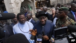 Nigerian President Goodluck Jonathan (C) and "ThisDay" newspaper owner Nduka Obaigbena (L) visit the site of an April 26 suicide attack which struck the newspaper's offices, in Abuja, on April 28, 2012.