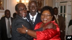 FILE: IN GOOD TIMES - Zimbabwean President Robert Mugabe, left, celebrates with newly sworn-in vice presidents Joyce Mujuru, right, and Joseph Msika, center, State House, Harare, Oct. 2008 file photo.