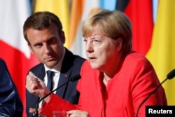 FILE - French President Emmanuel Macron and German Chancellor Angela Merkel attend a news conference following talks on European Union integration, defense and migration at the Elysee Palace in Paris, Aug. 28, 2017.