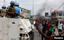 FILE - Residents chant slogans against Congolese President Joseph Kabila as UN peacekeepers patrol during demonstrations in the streets of the Democratic Republic of Congo's capital Kinshasa, Dec. 20, 2016.