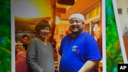 This photo provided by family shows Yoshihiko Takeuchi, right, posing for a photo with his friend Kayoko Kitatani, who visited his restaurant in Naha on the Okinawa islands, southern Japan, in 2015.
