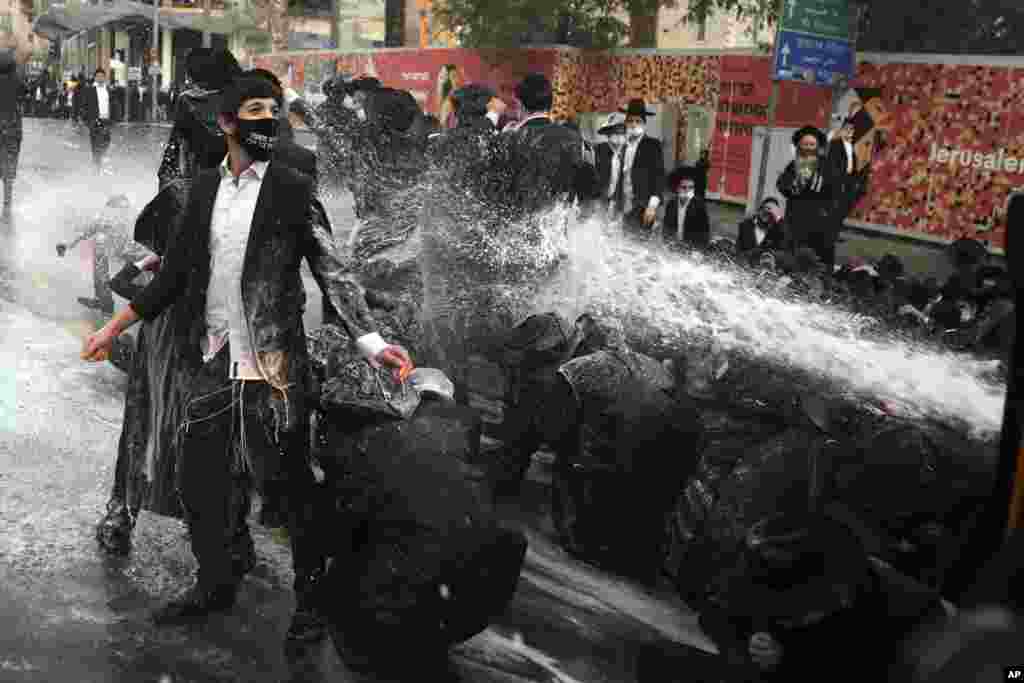 Israeli police shoot a water cannon towards ultra-Orthodox Jewish men blocking the road during a demonstration in Jerusalem.