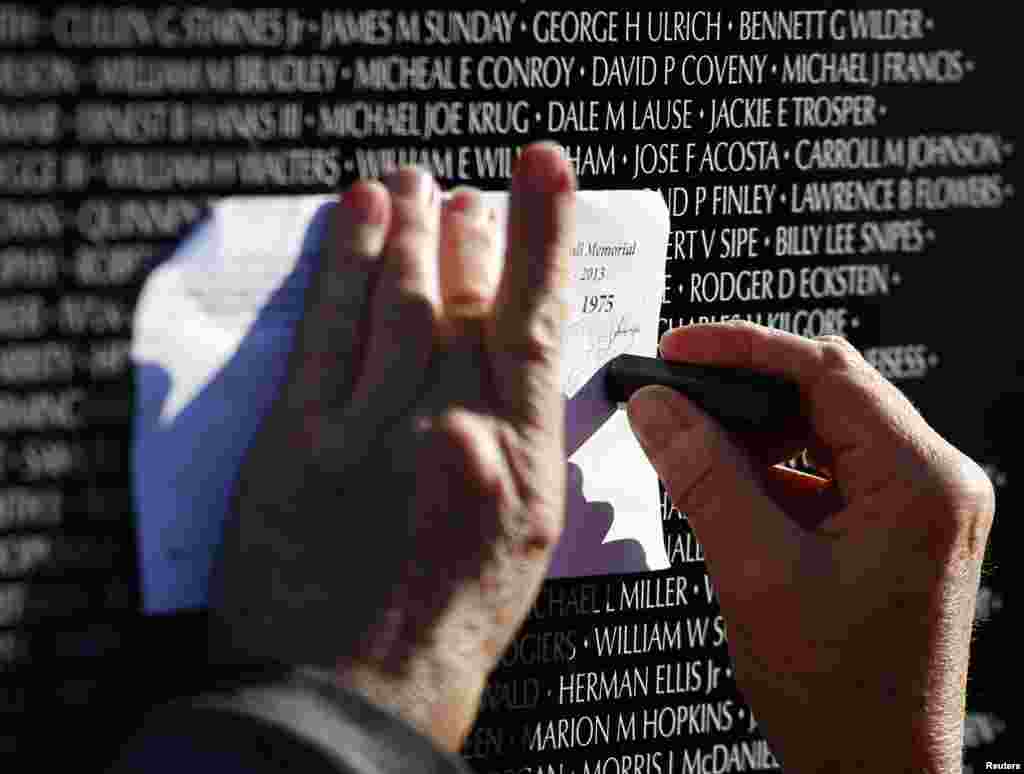 Chris Banholzer copies the name of a classmate from the Vietnam Moving Wall during Veterans Day weekend, Aurora, Illinois, Nov. 10, 2013. 