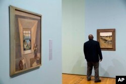 Niles Spencer's 1927 painting "The Dormer Window," left, and Andrew Wyeth's 1946 painting "The Stone Fence" are displayed at the High Museum of Art in Atlanta.