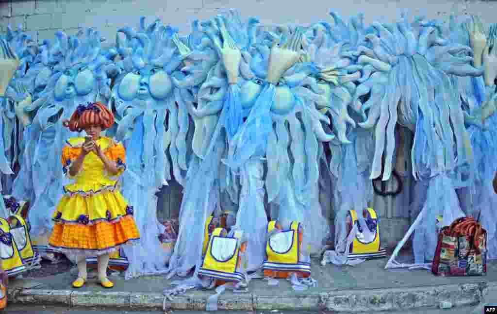 A performer waits in front of carnival costumes on the second night of Rio's Carnival at the Sambadrome in Rio de Janeiro, Brazil, Feb. 12, 2018.