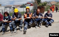 Rescuers rest and have food following an earthquake in Amatrice, central Italy, Aug. 25, 2016.