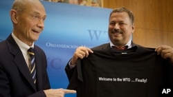 Pascal Lamy, left, Director-General of the World Trade Organization (WTO) hands over a t-shirt with a logo saying ' Welcome to the WTO...finally!' to Maxim Medvedkov, the Chief WTO negotiator for the Russian Federation in Geneva, Switzerland, November 10,