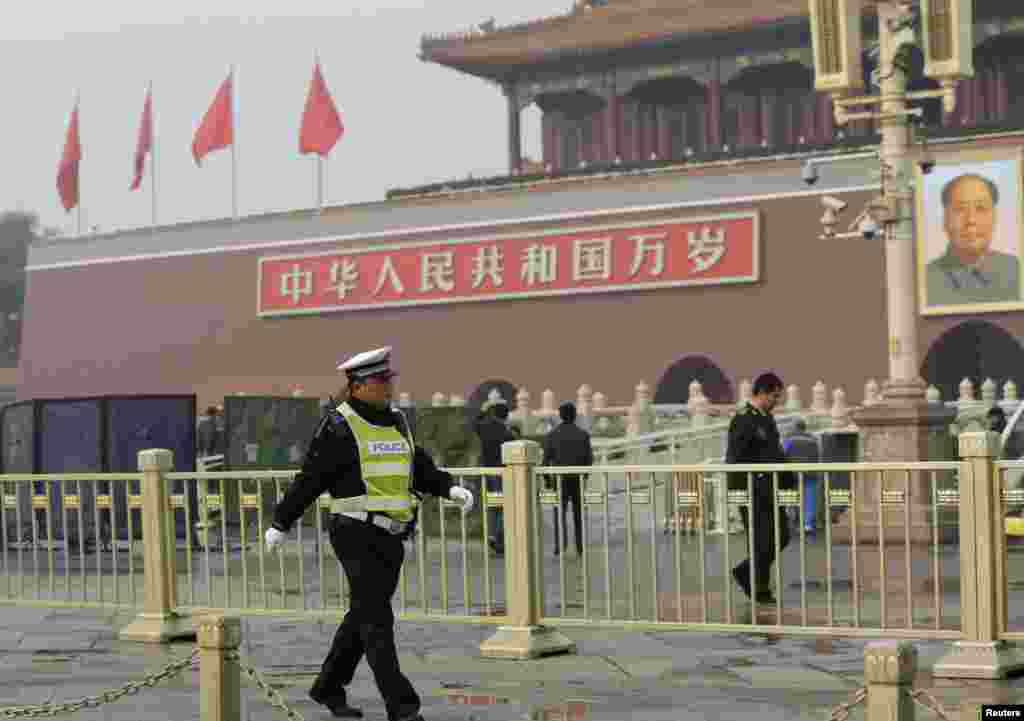 A police officer walks in front of the giant portrait of the late Chinese Chairman Mao Zedong as other police clean up after a car crash at Tiananmen Square in Beijing, Oct. 28, 2013.