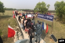 Rohingya refugees stand in line after they disembarked from a Bangladesh Navy ship to the island of Bashar Char in Noakhali on December 4, 2020.