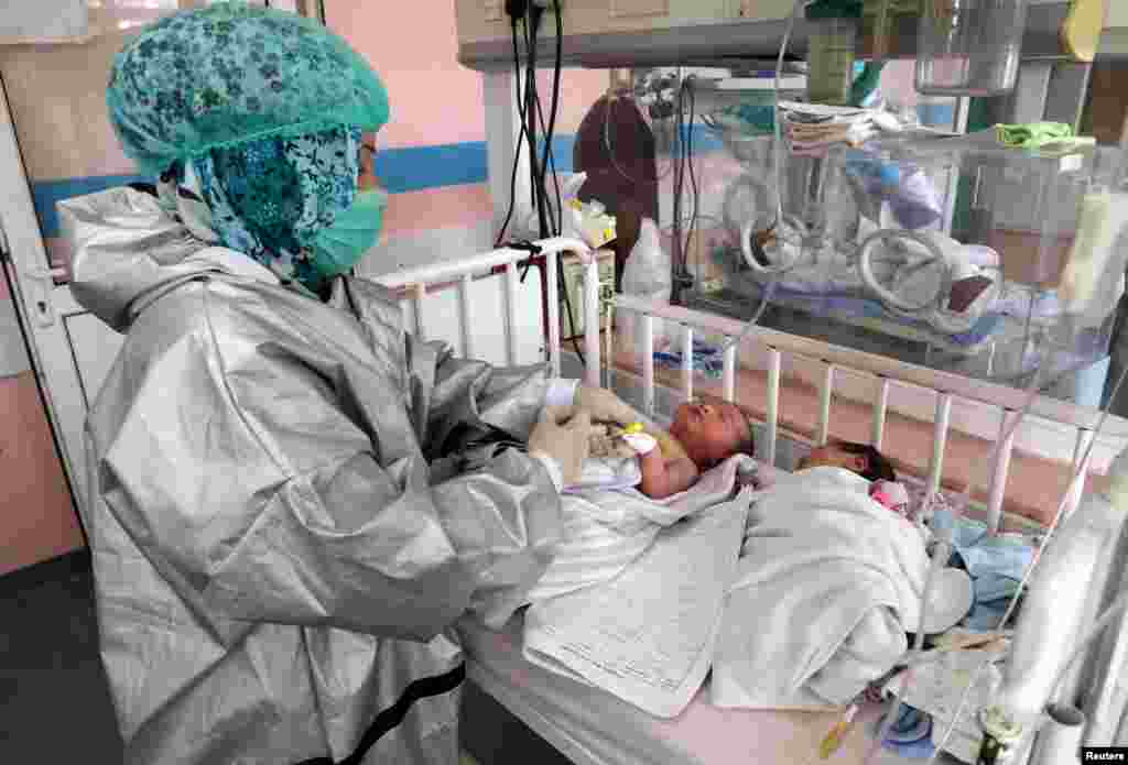 An Afghan nurse takes care of newborn children who lost their mothers in an attack at a hospital, in Kabul, Afghanistan. Gunmen burst into the hospital&rsquo;s maternity ward and started shooting. The attack killed 24 people, including two newborns. At least six babies lost their mothers.