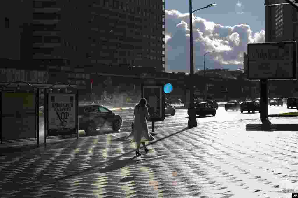 A young woman with a balloon walks along a street right after some rainfall in Moscow, Russia.