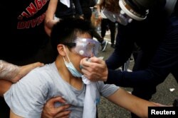 Protesters help a man during a demonstration against a proposed extradition bill where tear gas was fired, in Hong Kong, June 12, 2019.