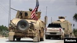 FILE - The U.S. flag flutters on a military vehicle in Manbij, Syria, May 12, 2018.