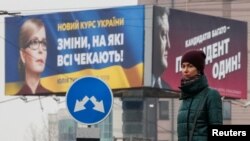 A woman stands in front of pre-election posters of opposition politician Yulia Tymoshenko and Ukrainian President Petro Poroshenko in Kyiv, Ukraine, Feb. 20, 2019. 