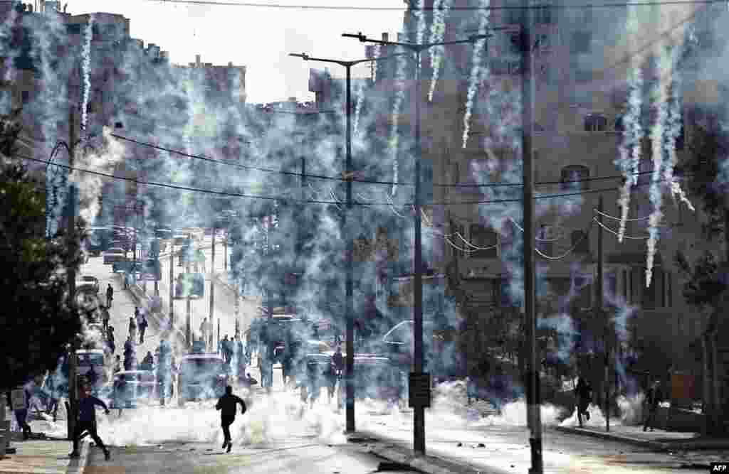 Palestinian stone-throwers run to take cover after Israeli security forces fired tear gas canisters during clashes following a demonstration next to the controversial Israeli separation wall in the West Bank city of Bethlehem.