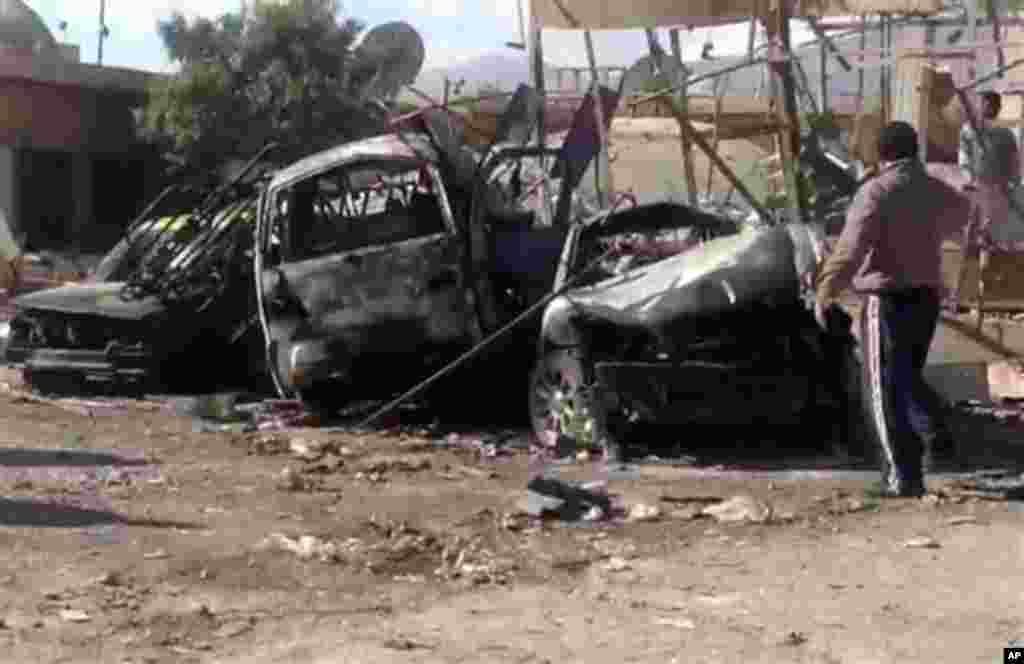 Syrian citizens gather next to cars that were destroyed by a car bomb in Qatana, (25) kilometers (15 miles) southwest of Damascus, Syria, Thursday, Dec. 13, 2012.&nbsp; (AP Photo/SANA)