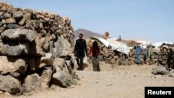 FILE - People walk at a makeshift camp for internally displaced people near Sana'a, Yemen, Jan. 28, 2019. 