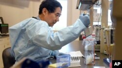 FILE: Microbiologist Xiugen Zhang runs a Polymerase Chain Reaction (PCR) test at the Connecticut State Public Health Laboratory, Monday, March 2, 2020, in Rocky Hill, Conn. 