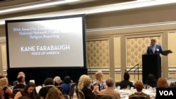 VOA's Kane Farabaugh accepts his award at the Religion News Association’s 70th annual awards banquet.