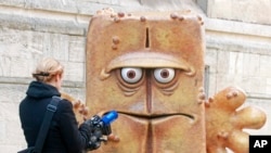 FILE - A journalist takes footage of a statue of "Bernd das Brot" in front of City Hall in Erfurt, Germany, Feb. 4, 2009. "Bernd das Brot" is a talking loaf of bread from a children's TV show. 