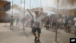 FILE - People cool off at the U.S. pavilion at the Expo 2015 world's fair in Rho, near Milan, Italy, July 4, 2015. A new study predicts more heat-related deaths in Europe by the year 2100.