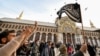 (FILE)A Syrian rebel fighter holds an Islamist black flag while walking in the courtyard of the 8th-century Umayyad Mosque in Damascus on December 10, 2024. 