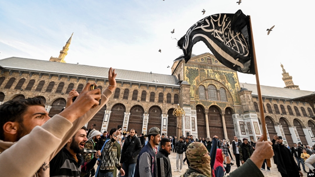 Sirijski pobunjenici sa islamističkom zastavom u dvorištu džamije Umajad u Damasku 10. decembra 2024. 