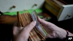 ARCHIVO - Un trabajador cuenta dinero en una tienda de comestibles en Buenos Aires, Argentina, el 21 de noviembre de 2023. 