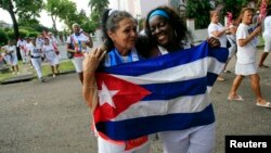 Recently released dissidents Haydee Gallardo (L) and Sonia Garro hold the Cuban national flag during a march in Havana, Jan. 11, 2015. 