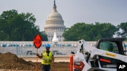 Workers repair a park near the Capitol in Washington, July 21, 2021, as senators struggle to reach a compromise over how to pay for nearly $1 trillion in public works spending, a key part of President Joe Biden's agenda.