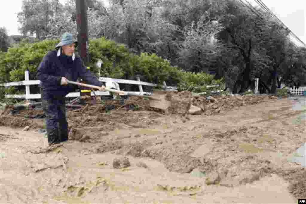 Resident Ben Viloria shovels mud to control flood waters from a hillside from entering his home in Modjeska Canyon, Calif., Wednesday, Dec. 22, 2010. (AP Photo/Alex Gallardo)