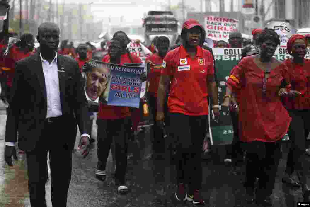 People walk in the rain during a protest for the release of secondary school girls abducted in the remote village of Chibok, along a road in Lagos, May 14, 2014.