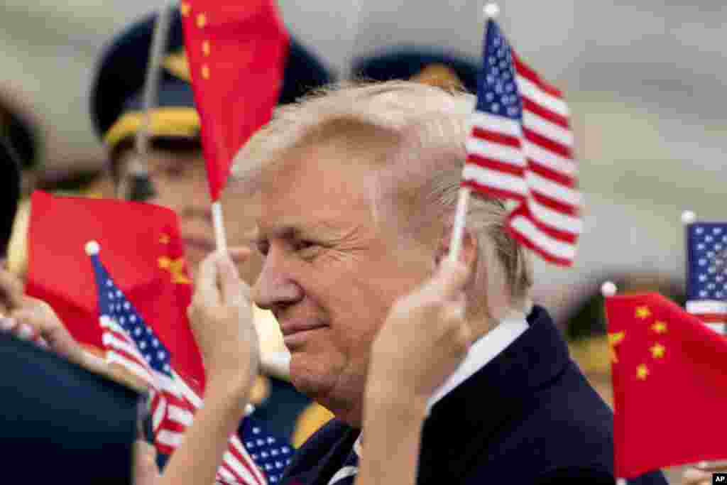 Anak-anak melambaikan bendera&nbsp;Amerika dan China pada saat Presiden Donald Trump tiba di Bandara Beijing, 8 November 2017.