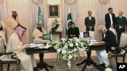 Visiting Saudi Arabia's Crown Prince Mohammed bin Salman, center left, and Pakistani Prime Minister Imran Khan, center right, witness the signing ceremony of the Memorandum of Understanding (MOU) on Petroleum, in Islamabad, Pakistan, Sunday, Feb. 17, 2019.